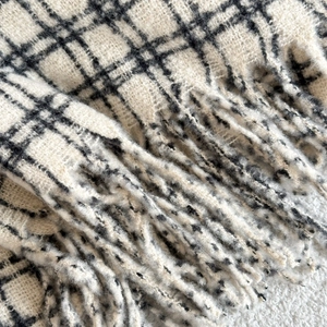 Close-up of soft black and white grid scarf with fluffy knit texture and long tassels