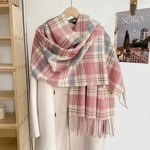 Detail of pink and grey plaid scarf with long tassels paired with white coat