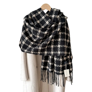 Classic black and beige plaid scarf with soft fringe, styled on a wooden hanger with a coat