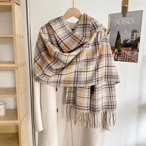 Close-up of a soft plaid scarf with tassels on a wool coat in a warm home setting