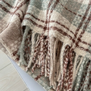 Detailed close-up of soft plaid scarf with long fringe tassels and warm knitted texture