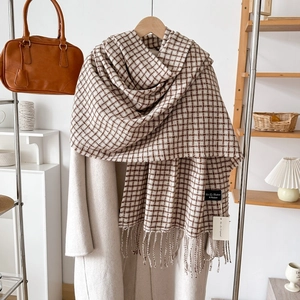 Écharpe à carreaux marron et beige effet cachemire avec franges sur un manteau