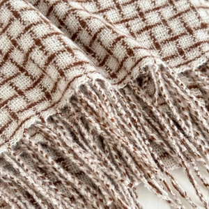 Gros plan sur le motif à carreaux marron et blanc avec franges douces de l'écharpe