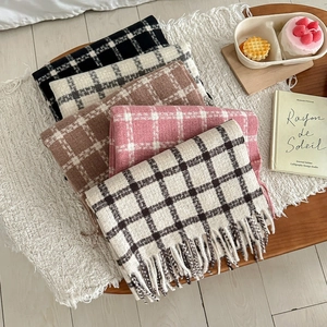 Detail view of five different colored plaid scarves with fringe tassels in soft warm fabric
