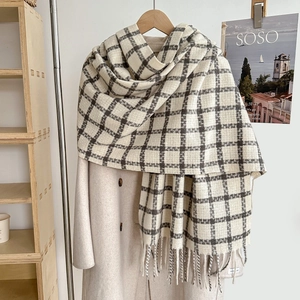 Detail of classic black and white plaid scarf with long fringe over a beige coat