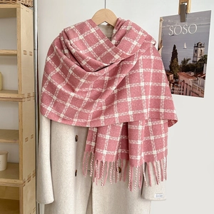 Thick pink and white plaid fringe scarf paired with a beige wool coat for winter style