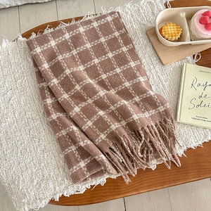 Close-up of thick plaid scarf texture with soft warm tassels on a cozy blanket