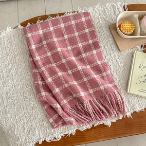 Detail view of pink and white plaid scarf with soft fringe edges on a cozy background
