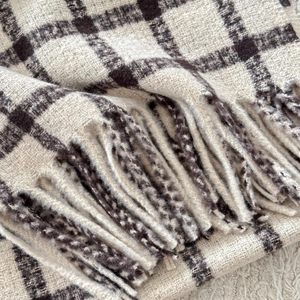 Close-up of thick plaid cashmere-like scarf with fringe details in cream and brown