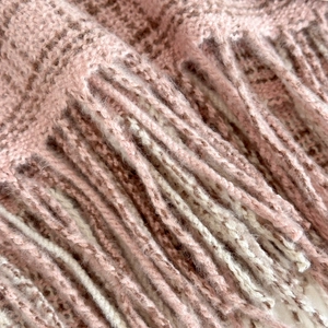 Detail of pink and beige plaid winter scarf with soft fringe edges and knit texture