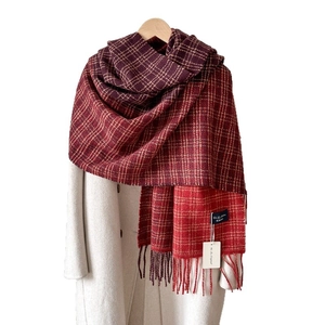 Classic red and brown checkered scarf with fringe on white coat and wooden hanger