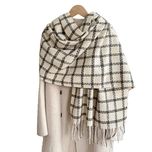 Thick soft plaid cashmere scarf with tassels and handmade label on beige coat