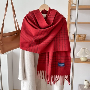 Detail of red plaid scarf with fringes styled on a coat for an autumn winter look