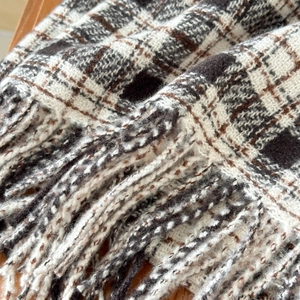 Close-up of thick plaid scarf with soft cashmere texture and fine fringe details