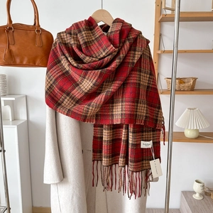 Detail shot of soft red plaid cashmere-like scarf with long fringe and classic pattern