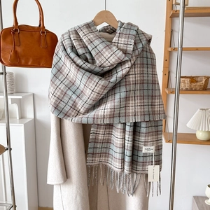 Classic plaid tassel scarf in soft cashmere-like fabric on minimalist beige coat