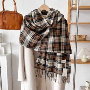 Detail of brown plaid scarf with tassels and brand tag on a stylish wool coat