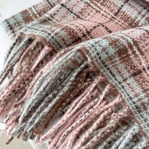 Close-up of pink and grey checkered scarf showing soft tassels and cashmere-like texture