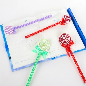 Creative lollipop-shaped ballpoint pens set with polka dot bows on a blue notebook