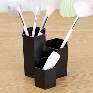 Black hexagonal makeup brush holder with three-tier compartments on wooden desk