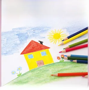 Close-up of vibrant colored pencils set next to a creative child drawing of a house