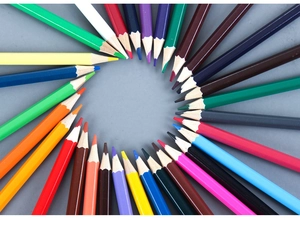 Top view of vibrant colored pencils arranged in a circular radial pattern on gray background