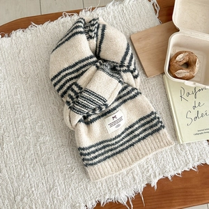 Detailed close-up of striped wool blend knit scarf with label on a cozy blanket