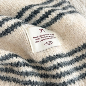 Close-up of soft striped wool blend knit texture with a white woven brand label