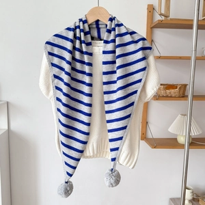 Détail d'une écharpe triangle en tricot à rayures bleu-gris avec pompons gris sur les bords