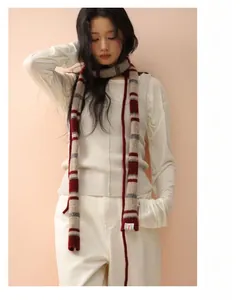 Detailaufnahme des gestreiften Wollschals in Rot, Grau und Creme mit weicher Textur