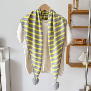 Détail d'une écharpe triangle en tricot à rayures jaune et gris avec pompons décoratifs