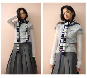 Detail eines gestreiften Wollschals kombiniert mit grauer Strickweste im College-Stil