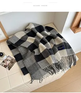Close-up of black and grey checkered scarf with soft tassels and woven logo label