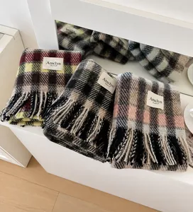 Detailed view of plaid tassel scarves in red, green, and pink colors for winter