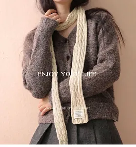 Detailed close-up of cream knit scarf with classic cable stitch and fabric patch detail