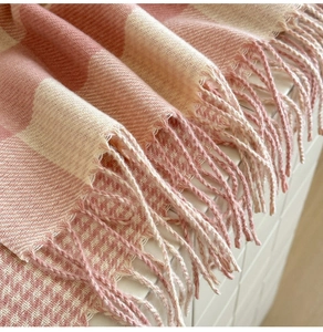 Detail shot of pink and white plaid scarf featuring soft knit texture and fringe tassels