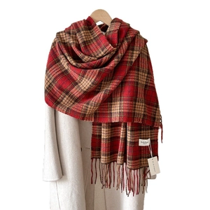 Plaid cashmere feel scarf with fringe on white coat and wooden hanger for winter