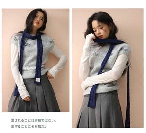 Detail view of dark blue cable knit scarf and grey textured vest in a daily outfit