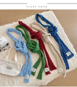 Detail of five colored cable knit scarves with decorative labels on a cozy rug