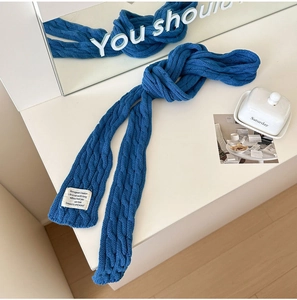 Macro view of blue chunky cable knit scarf texture with a white woven brand label