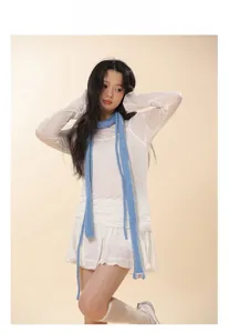 Detailed knit texture of a slim blue wool scarf paired with a white pleated skirt set
