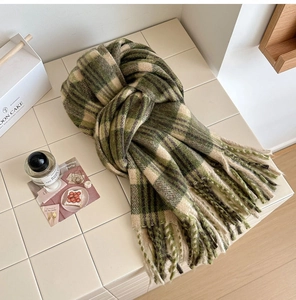 Détail d'une écharpe douce à carreaux verts et beige avec de longues franges