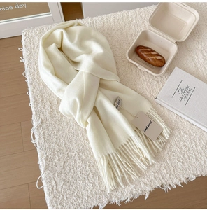 Close-up of a soft cream wool scarf with tassels and an authentic brand hangtag