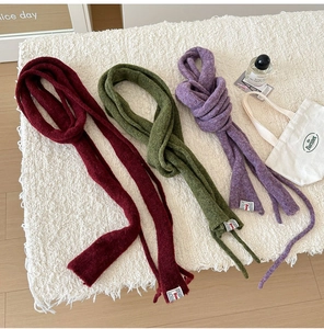 Detailed knit texture of slim wool scarves in burgundy, moss green, and lilac purple