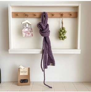 Detailed texture of purple chunky knit wool scarf hanging on a wooden wall hook