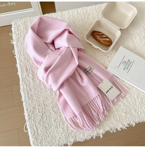 Close-up of soft pink wool scarf with elegant tassels and minimalist product label