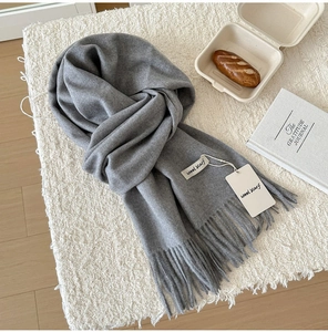 Detailed macro of a soft grey wool scarf with fine fringe on a cozy lifestyle background