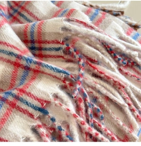 Vue détaillée de la texture douce de l'écharpe en laine à carreaux rouge et bleu à franges