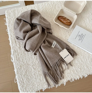 Detail of dark camel wool scarf with fringe edges and premium material tag