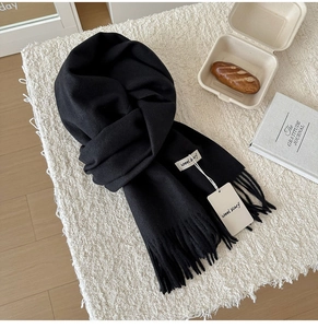 Detail of soft black wool scarf showing the fringe edges and premium woven label